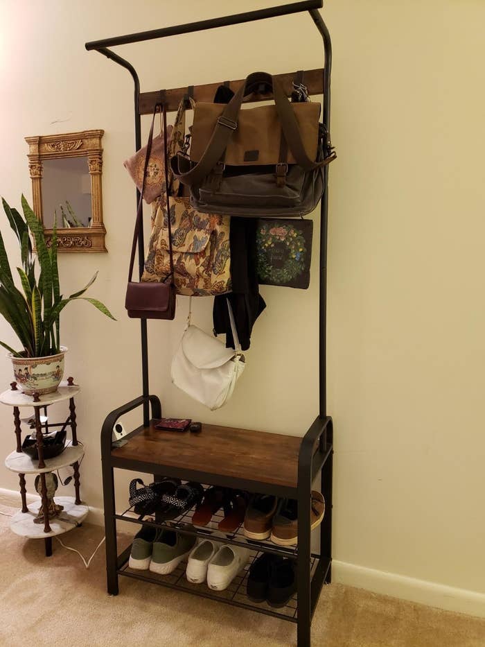 reviewer photo of a coat rack with bags hanging on the racks and shoes on the shelves