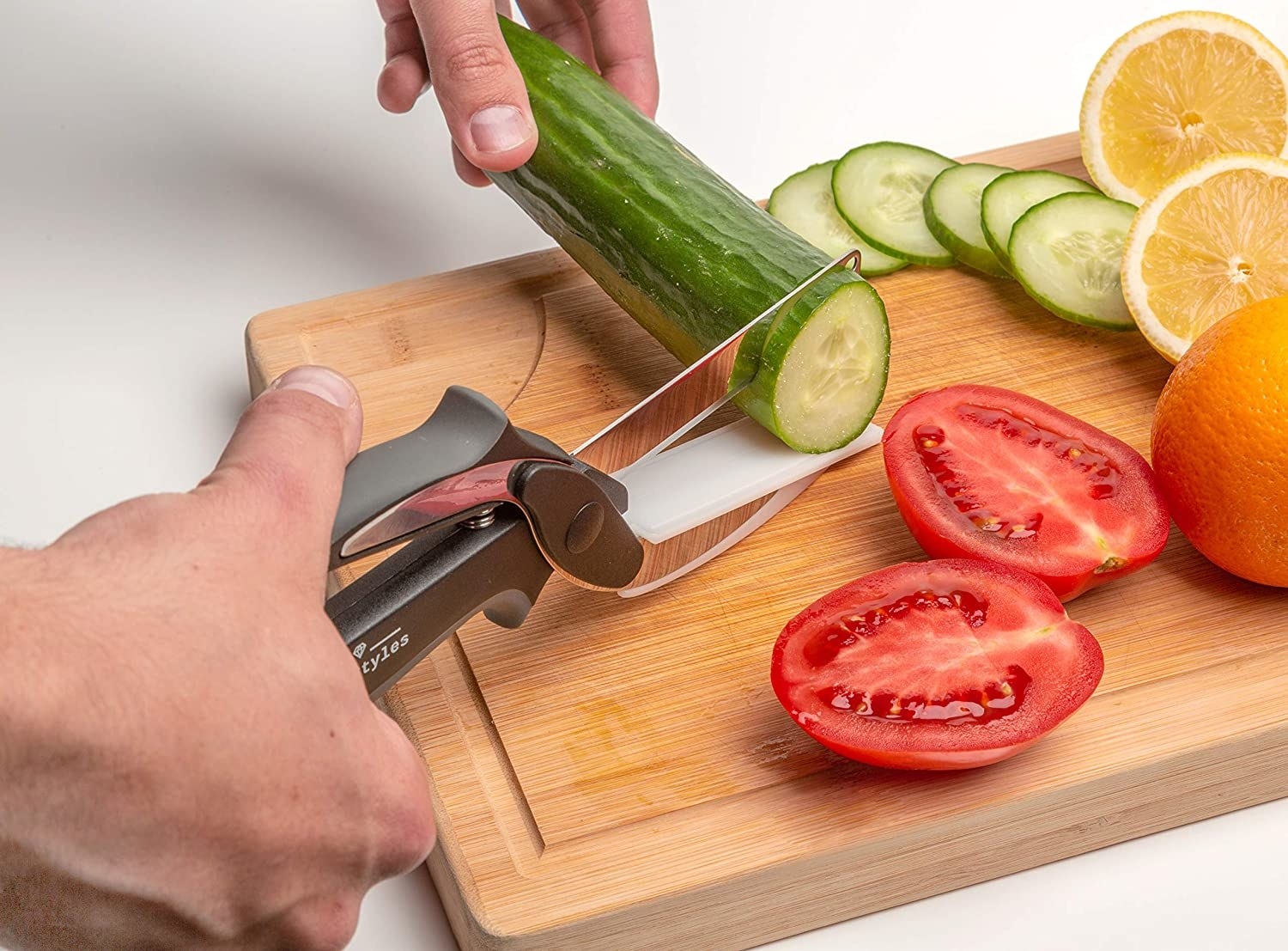 the half knife, half scissor tool being used to cut a cucumber