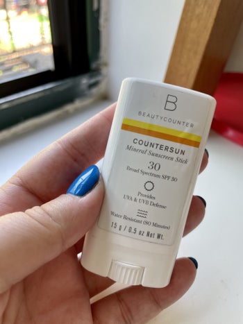 a buzzfeed editor holding the small sunscreen stick