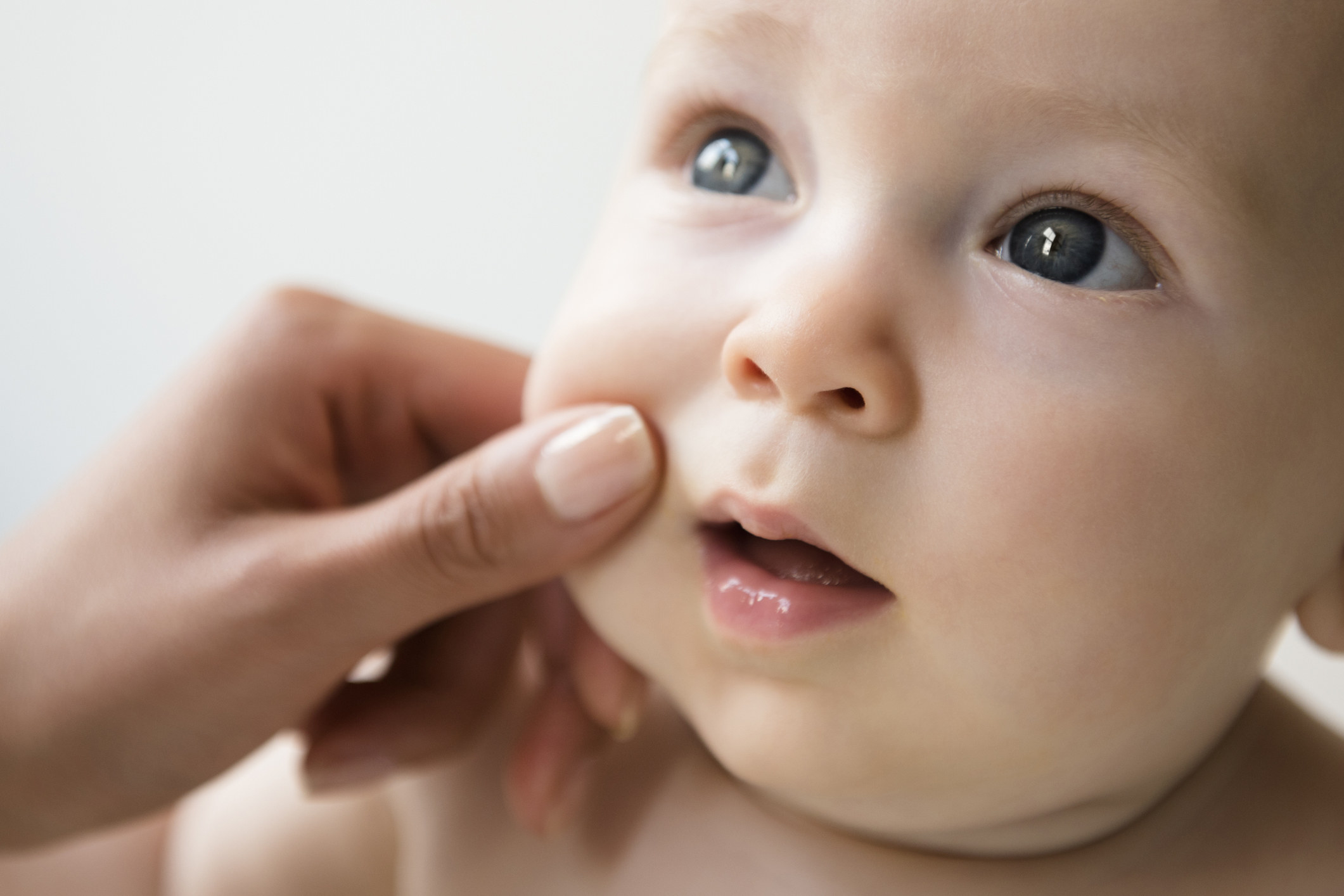 Someone pinching a baby&#x27;s cheeks 