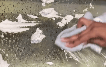 gif of a hand wiping an oven door clean using the oven scrub