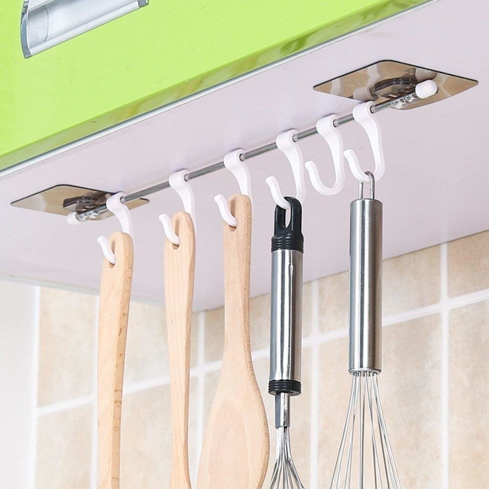 The hooks are stuck underneath a kitchen cabinet. They&#x27;re used to hang up kitchen tools like stirring spoons and whisks.
