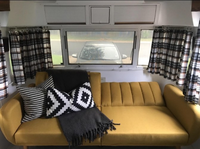 A reviewer’s photo of a yellow sofa futon inside a trailer 