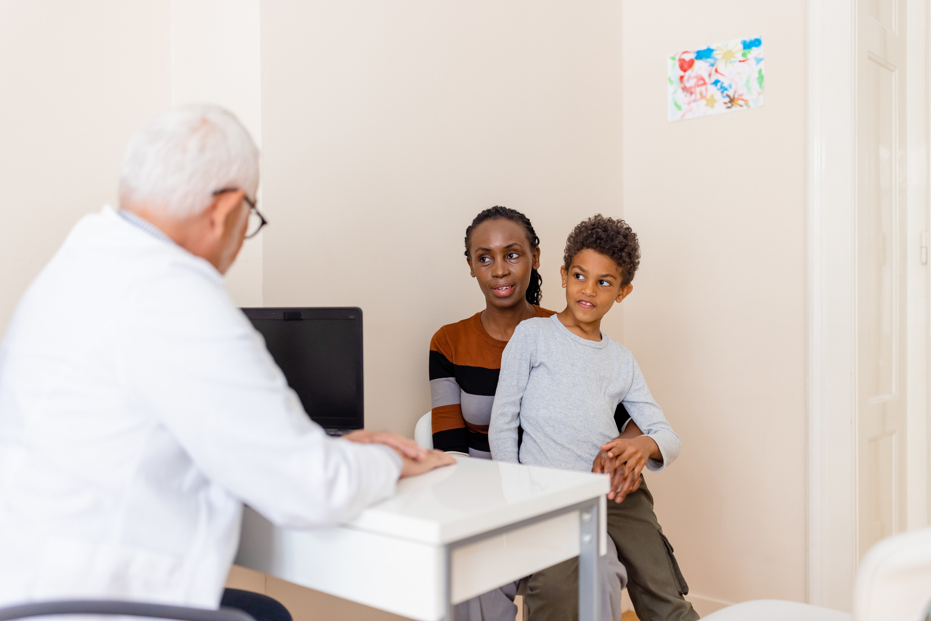 A mom and her son staring uncomfortably at the doctor 