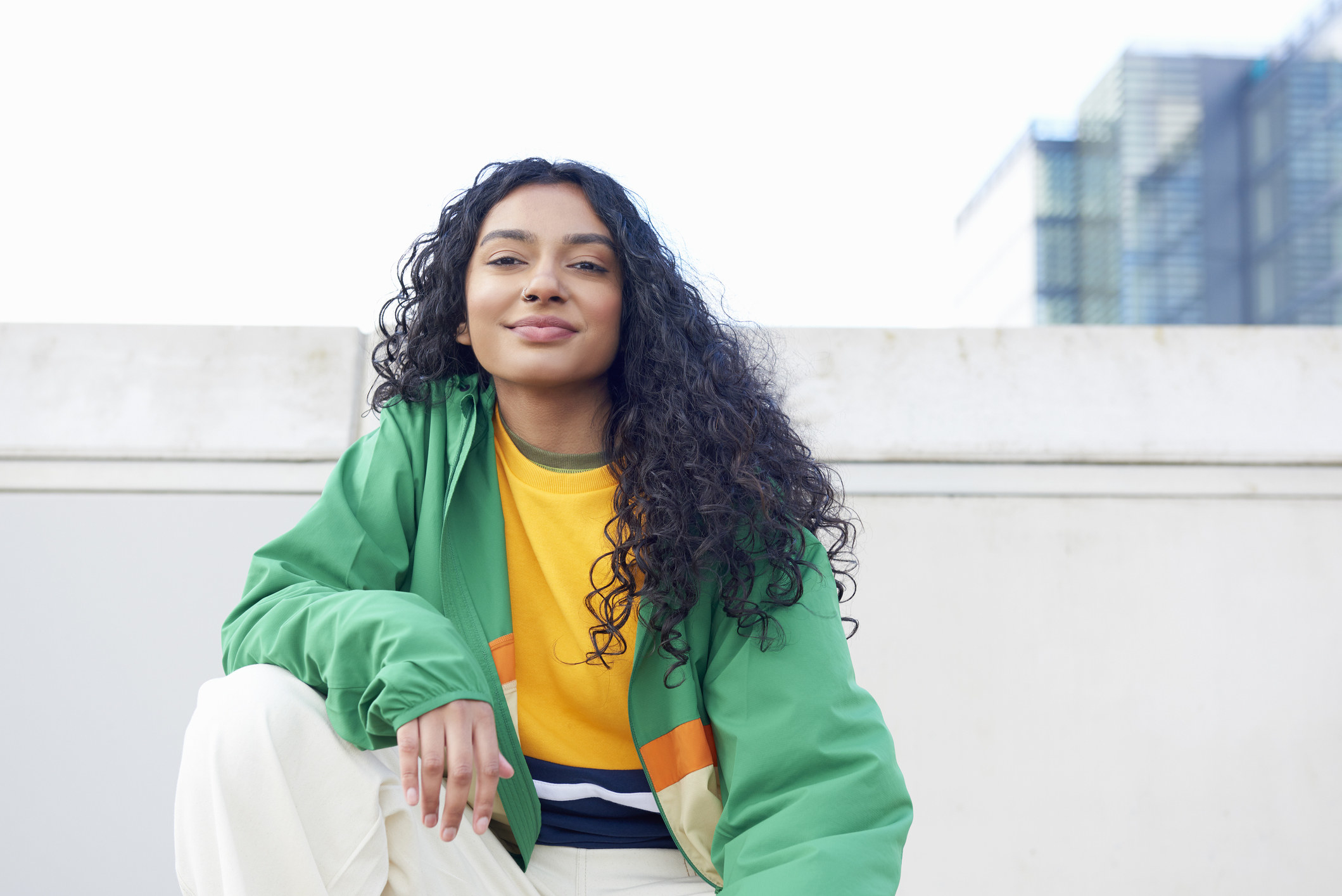 A young woman posing on a roof and smiling at the camera