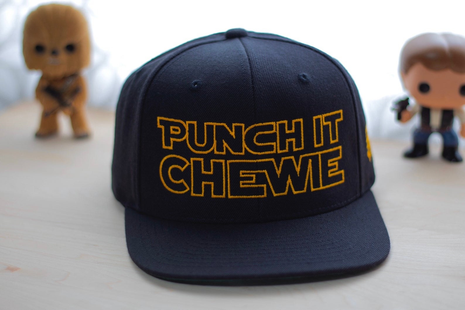 a black hat with yellow writing that says punch it chewie