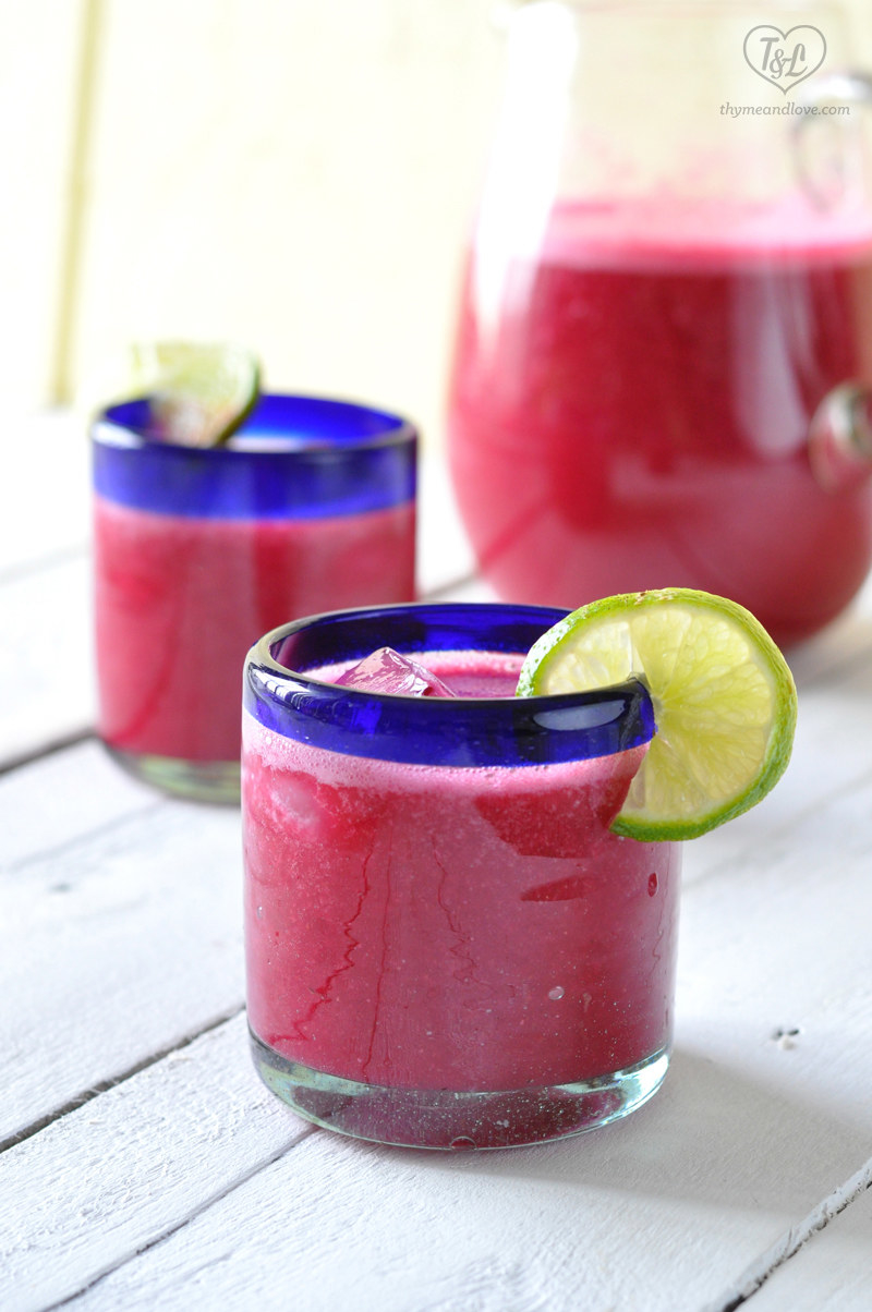 Fancy short glass with blue rim containing prickly pear and strawberry agua fresca