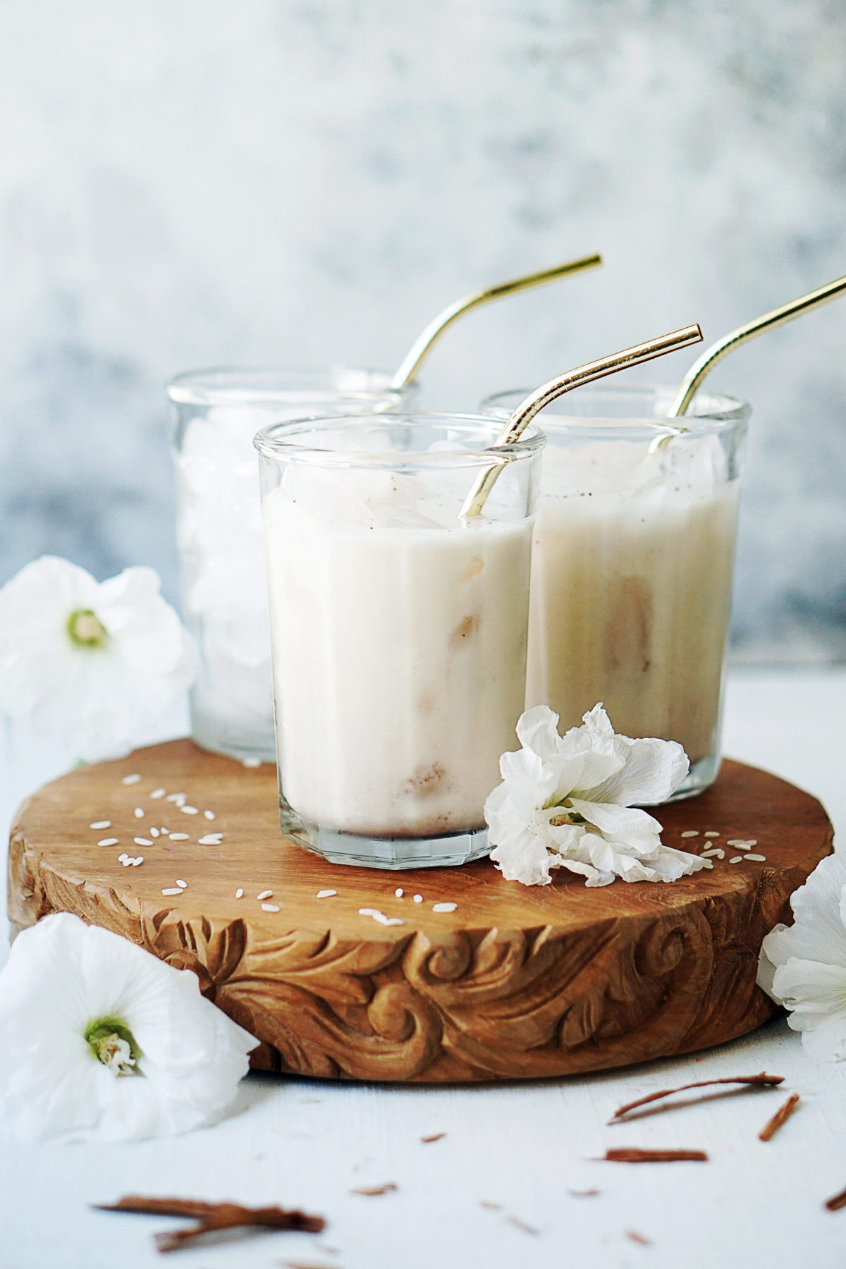 Two glasses of fresh horchata with metal straws and white flowers placed at front of glasses