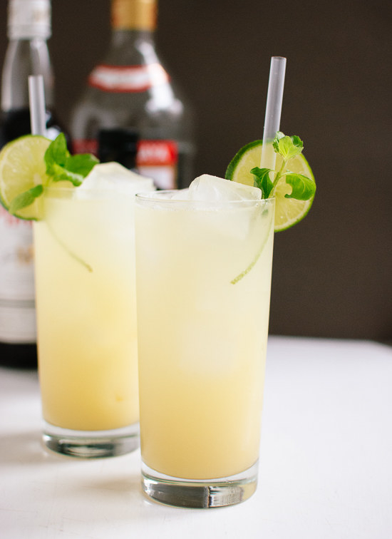 Two tall collins glasses of ginger beer, decorated with lime slices