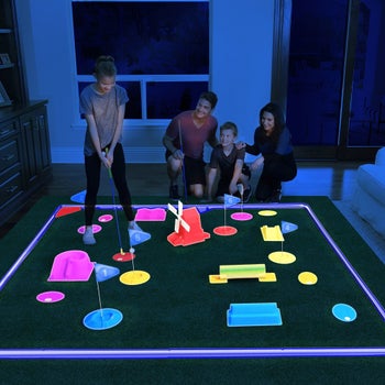 a family playing with the golf set in the dark indoors