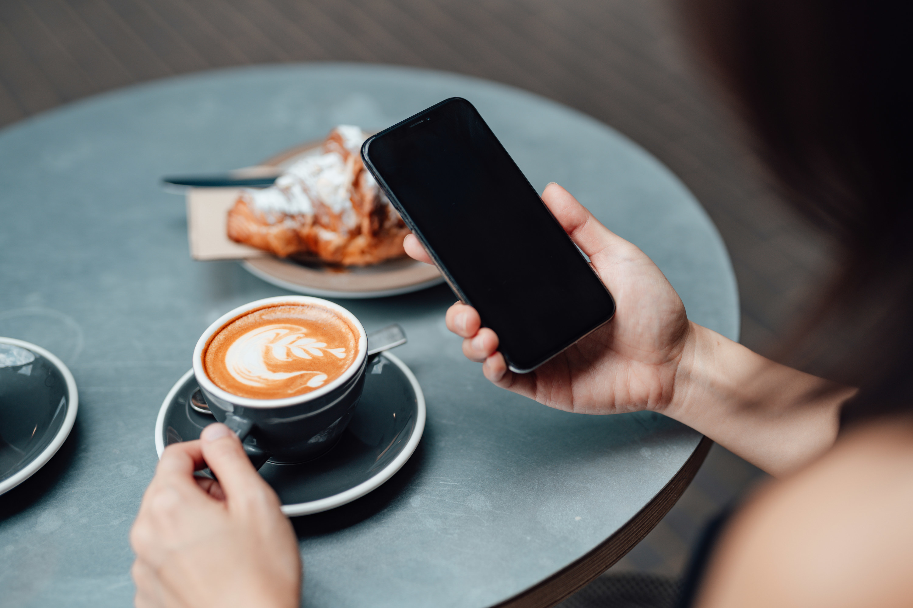 Photo of a cafe table and woman holding a phone 