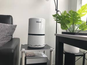 reviewer photo of a white levoit air purifier sitting on a side table