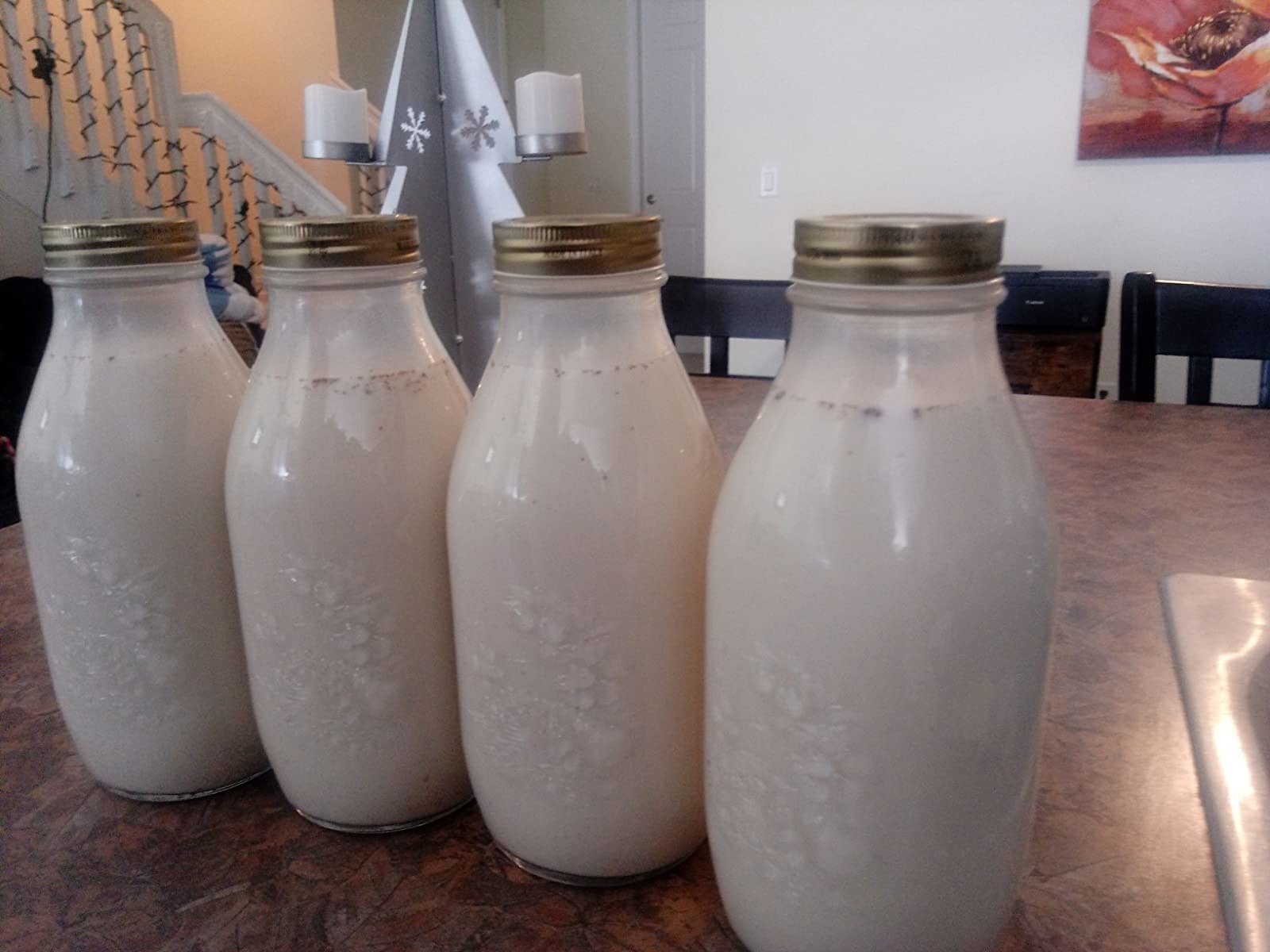 A reviewer photo of four of the milk jugs filled with egg nog, with the lids screwed on