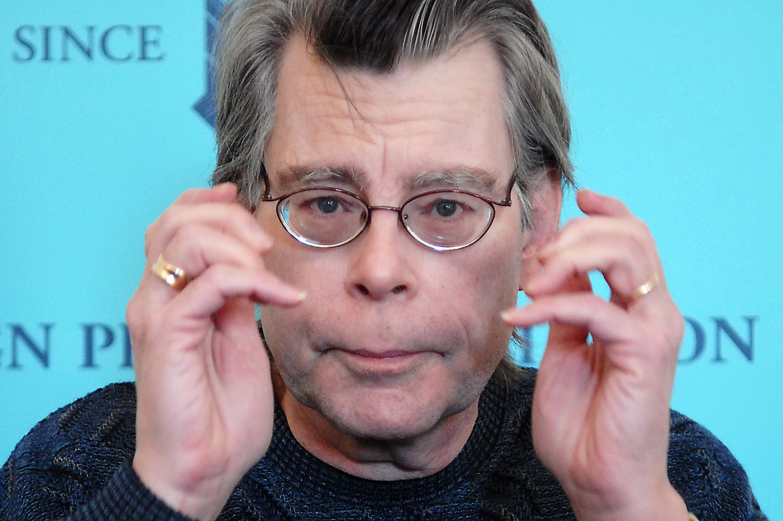 Stephen King holding his hands up near his face