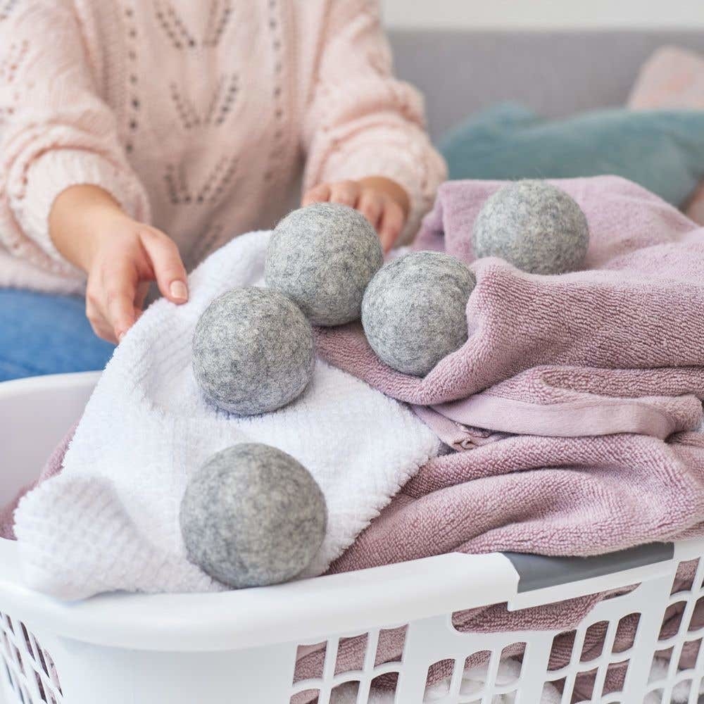 A bunch of wool dryer balls sitting on top of a pile of clean laundry in a basket