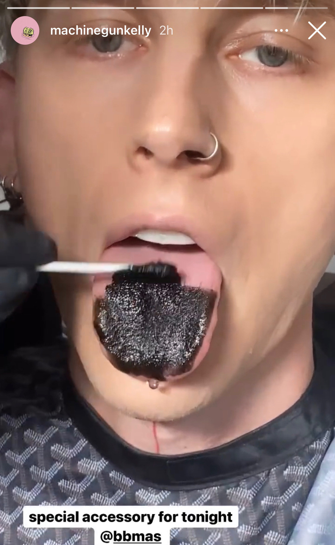 Machine Gun Kelly having his tongue painted black with a swab