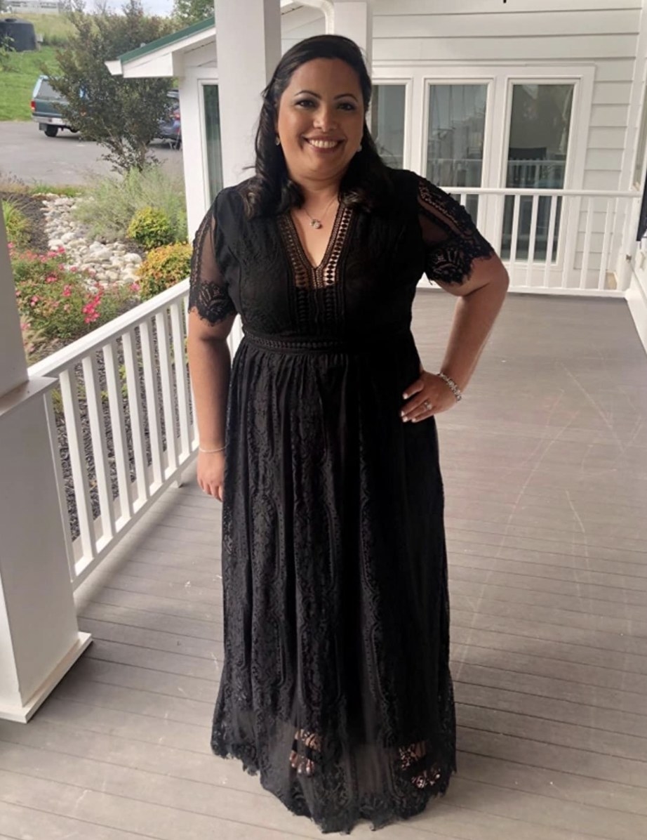reviewer wearing a black lacy floor-length dress with short sleeves