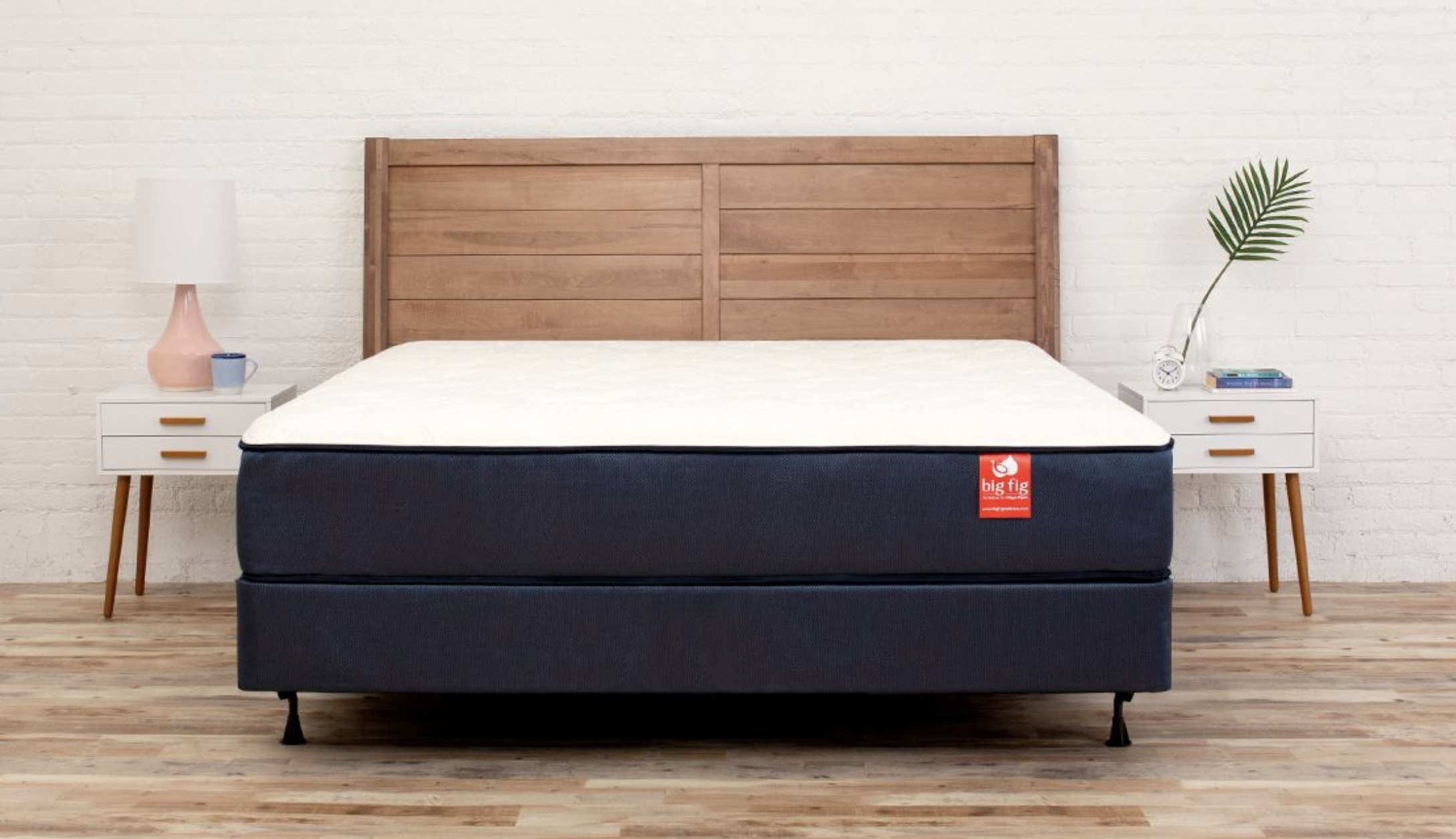 A white mattress with black trim on a bed frame 
