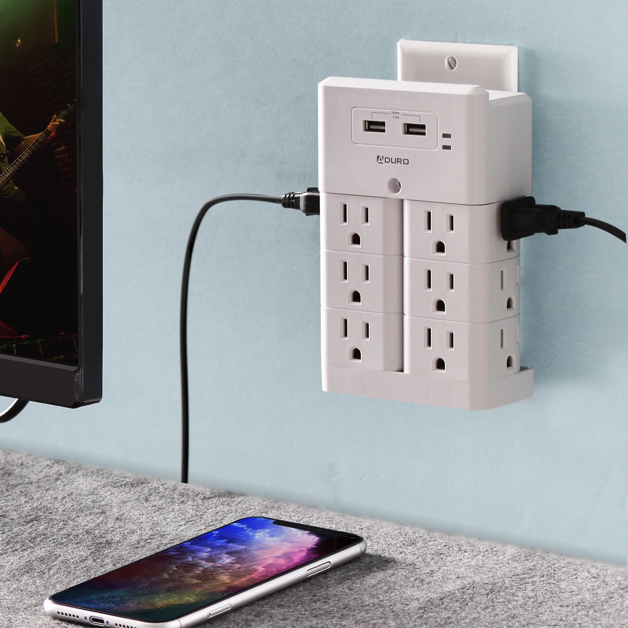 the white aduro surge protector plugged into a wall near a mounted TV