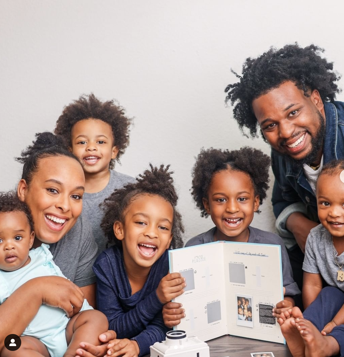 A family posed with a notebook open to show pictures and writing in it 