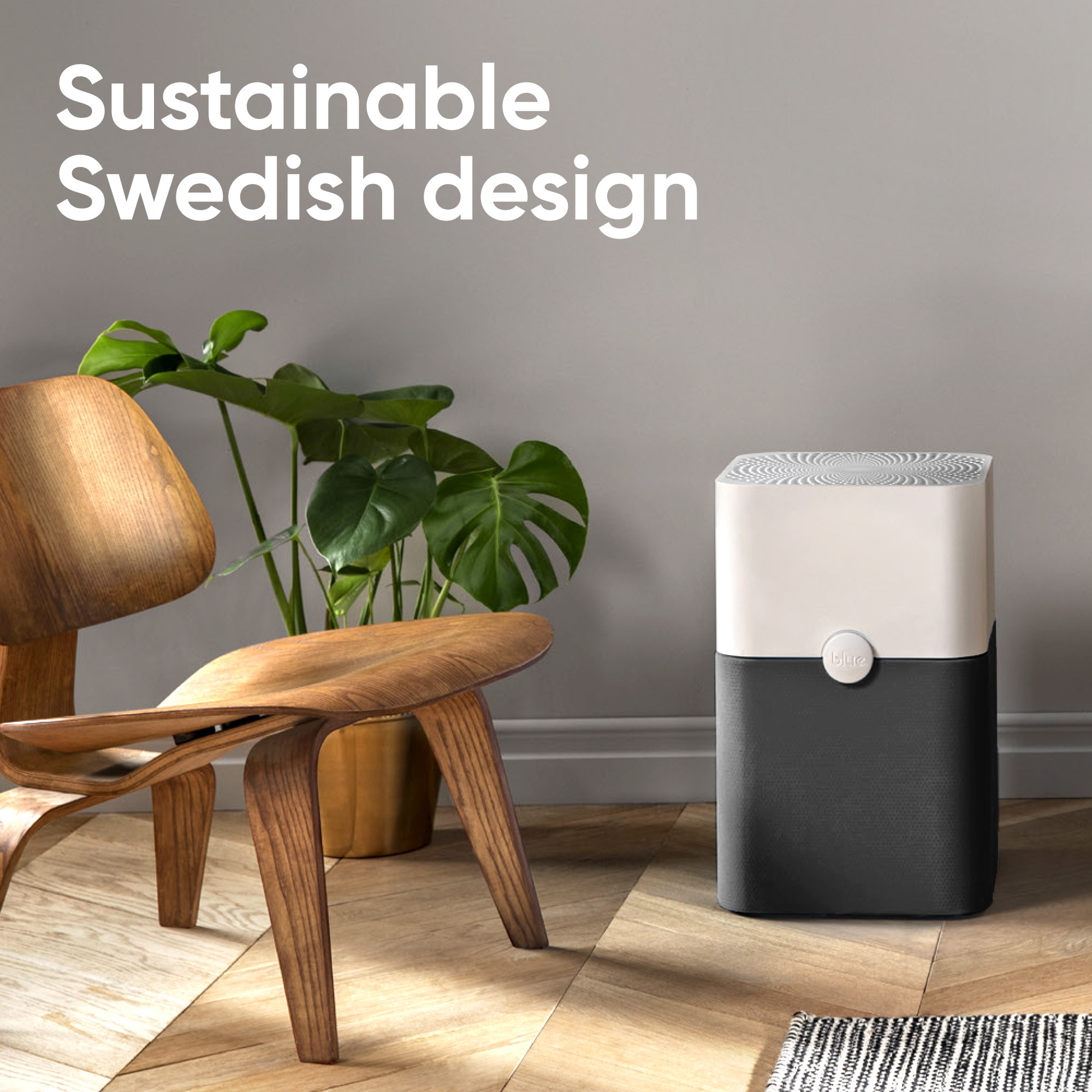 the blueair air purifier in a living space next to a wooden chair and a plant with text that reads &quot;sustainable swedish design&quot;