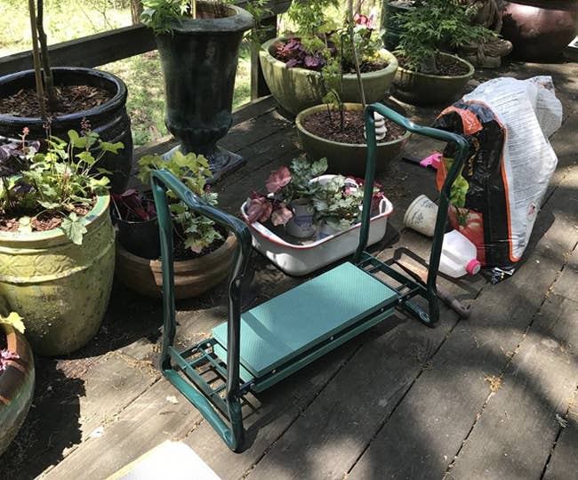 a kneeler bench for gardening next to potted plants