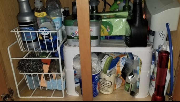 A reviewer&#x27;s under-sink organizer underneath their sink with cleaning products
