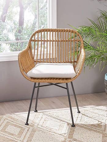 one chair with tan weaving. It has a back, arms, and a tan or white cushion in the seat, with black metal legs