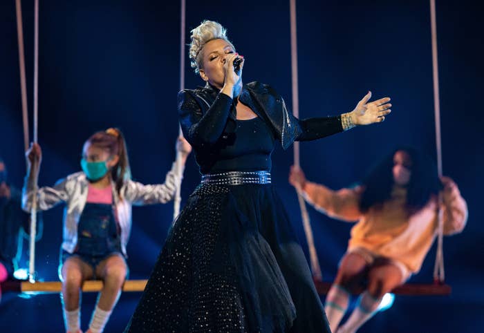 Pink performs a song on stage in a black dress and leather jacket