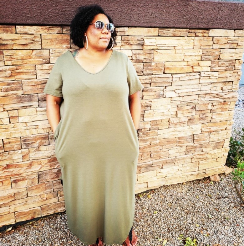 A reviewer wearing the dress in green 