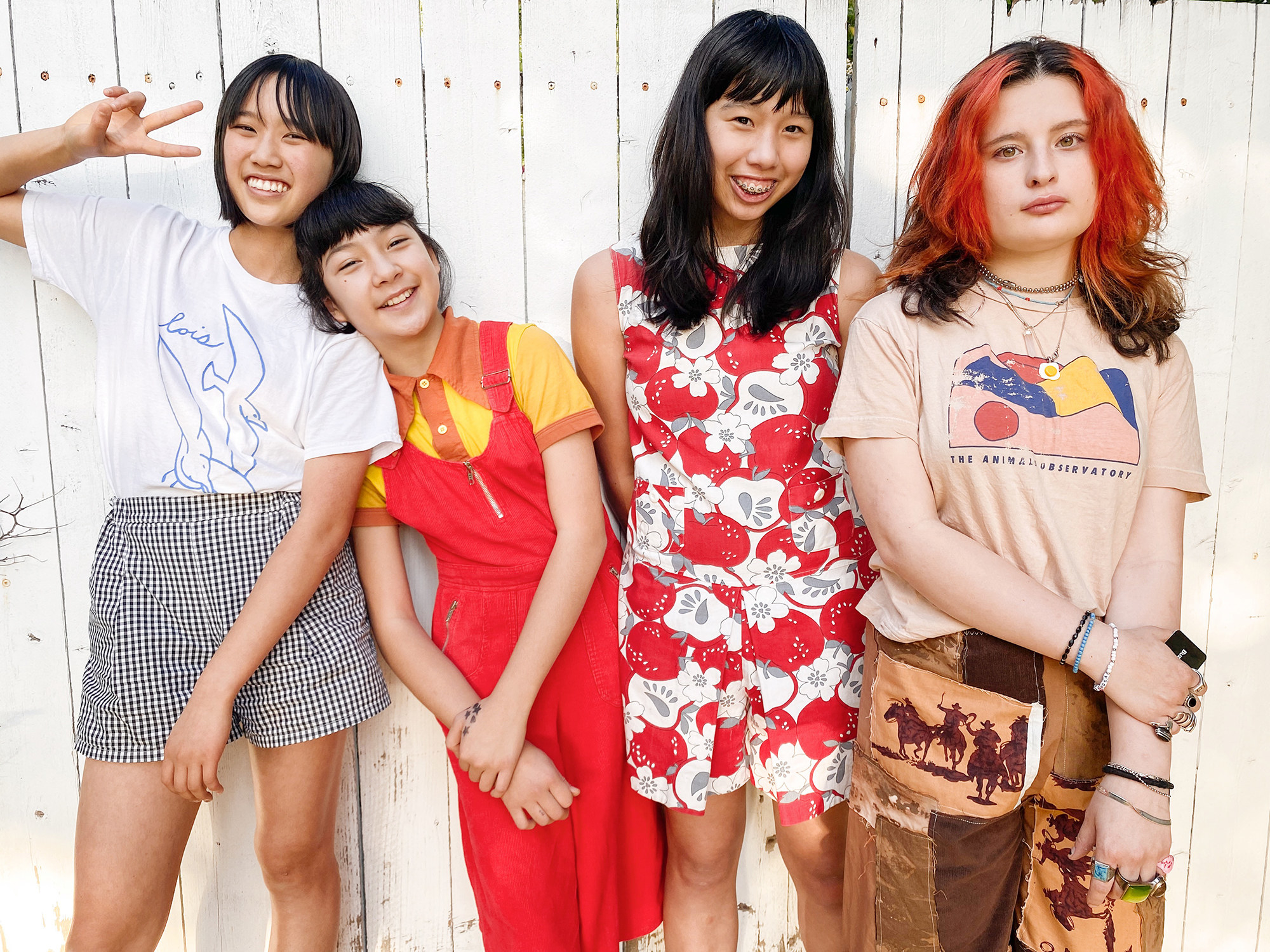 Four girls pose for a portrait next to a picket fence 