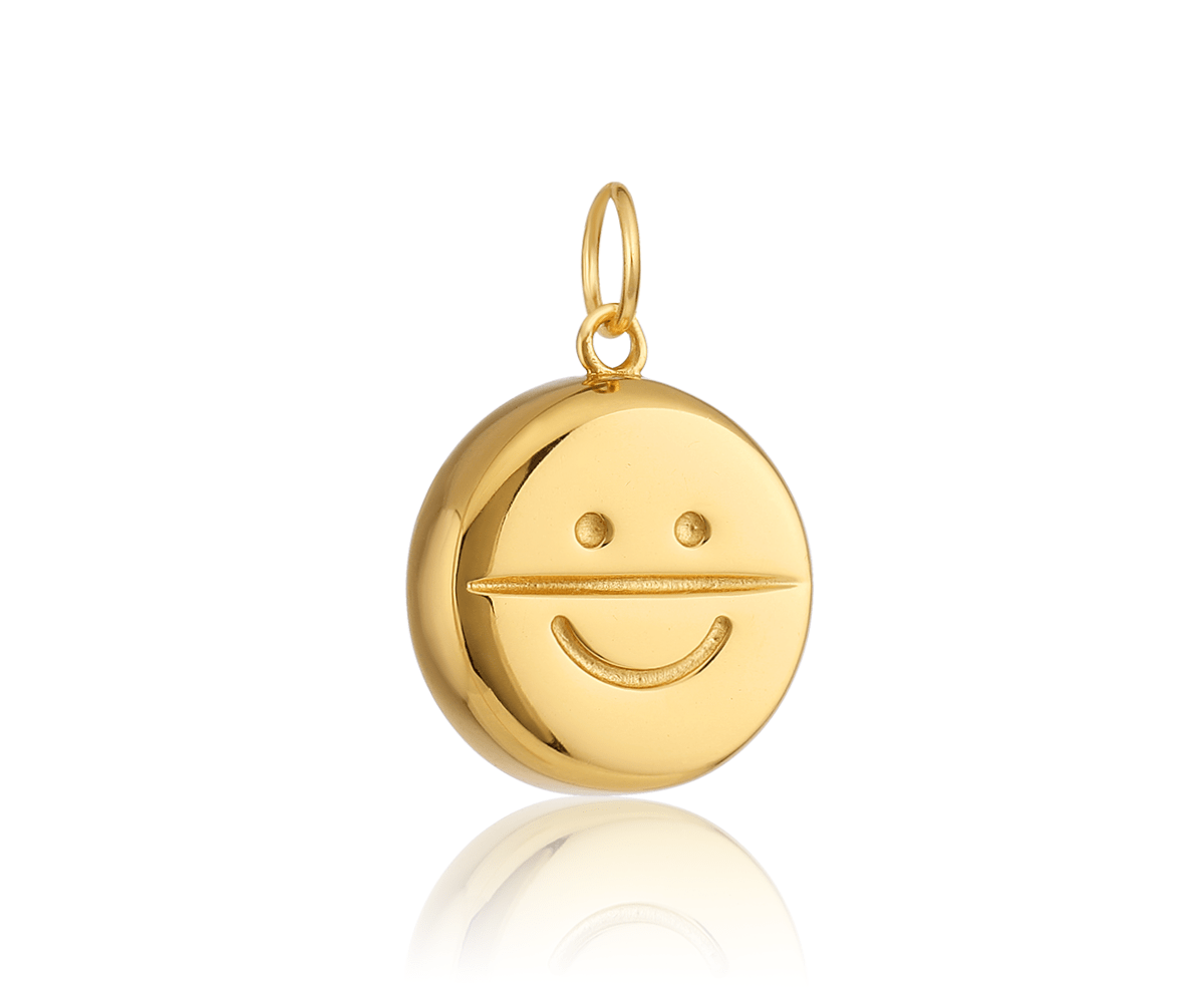 a gold pill-shaped charm with a smiley face on it