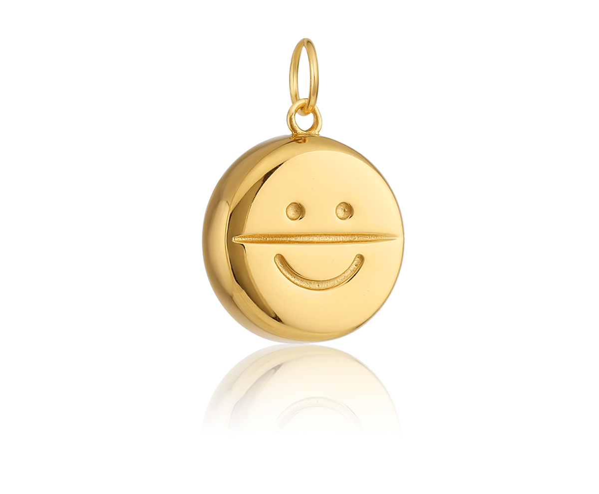 a gold pill-shaped charm with a smiley face on it