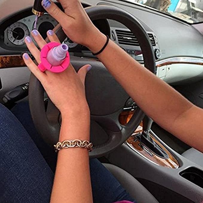 A person wearing the nail polish holder like a ring with the nail polish bottle secured in the middle.