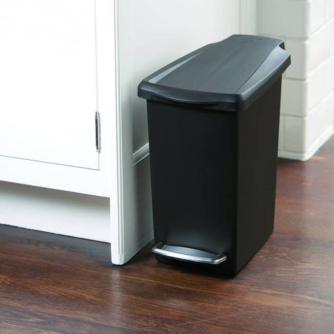 Small black trash can with foot lever and lid 