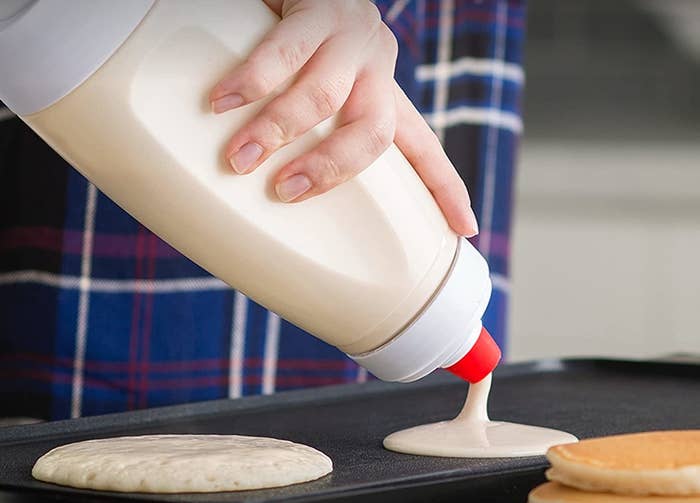 person pouring out pancakes on a griddle