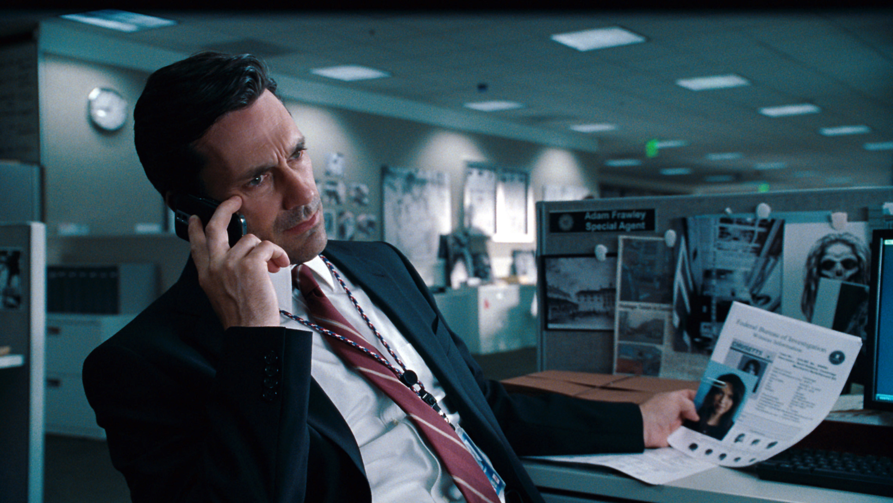 Jon Hamm as Adam Frawley, sitting in an office and talking on the phone
