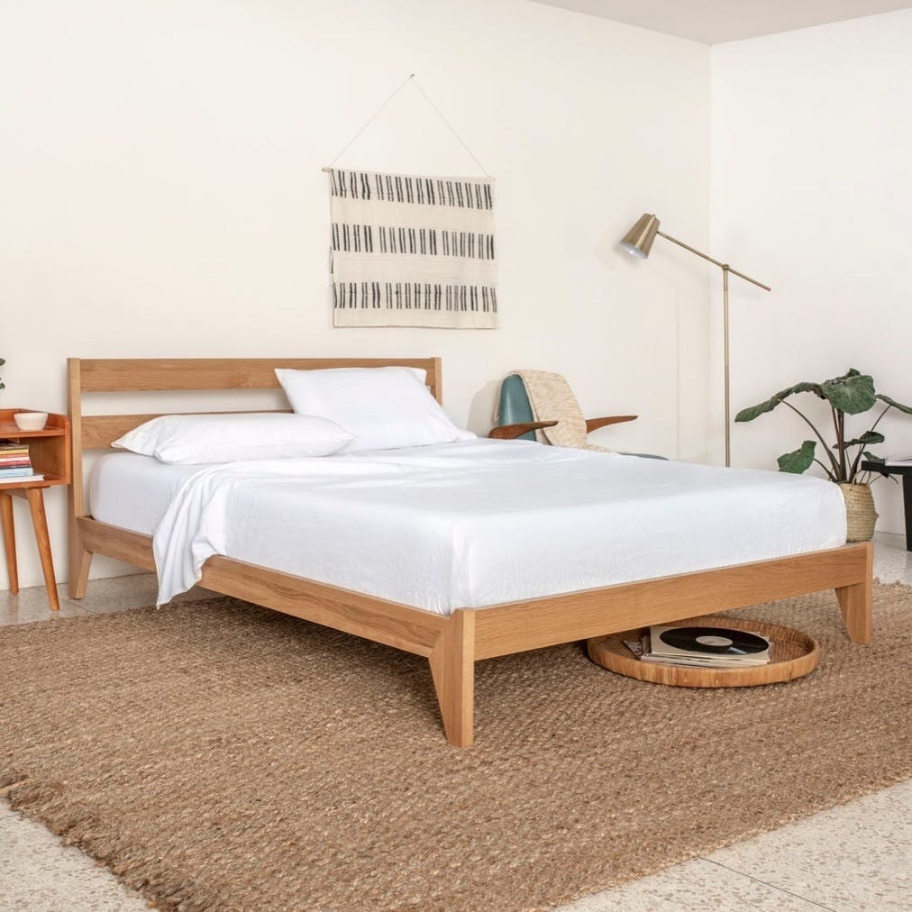 Wooden bed frame with white sheets on bed 