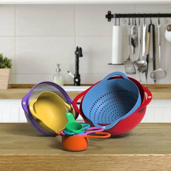 The nested cookware in a kitchen with each piece a different color of the rainbow 