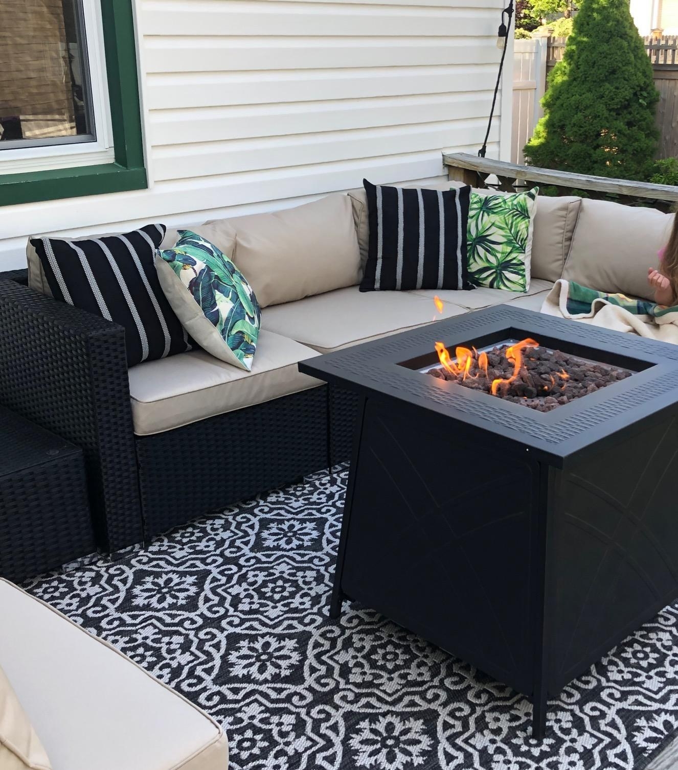 The black and white printed rug with a medallion motif pattern under an outdoor fire pit and patio furniture