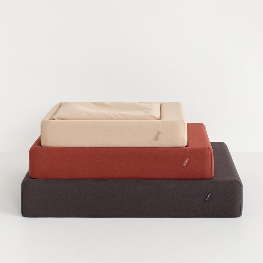 Three dog beds in gray, red and beige from larger size to smallest size top to bottom