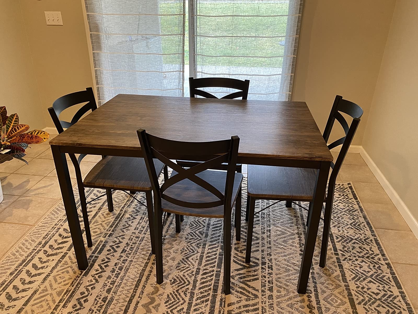 The dinning set with a table and four chairs that each have wood surfaces and black metal frames