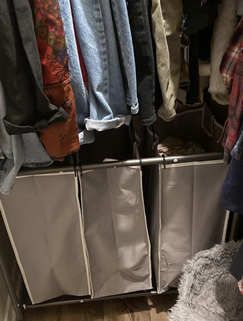 A metal wheeling cart with three beige bags in a closet 