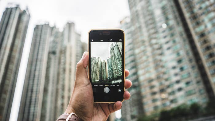 A photo of a smartphone&#x27;s camera app taking a photo of many high rise buildings.