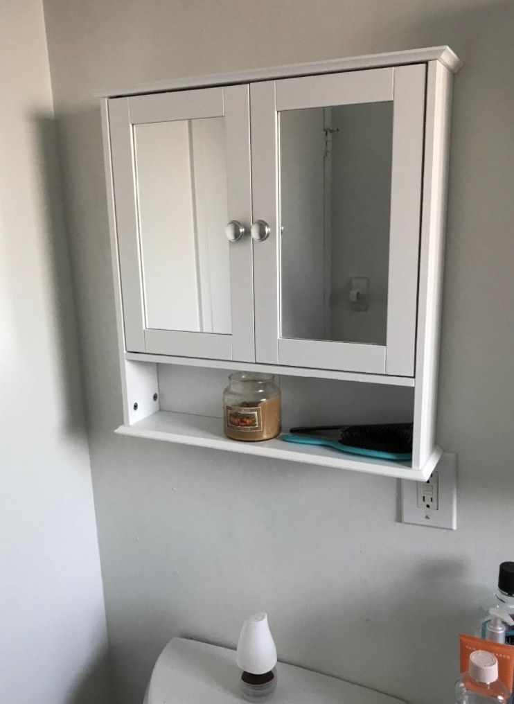 a white medicine cabinet with doors and an open shelf
