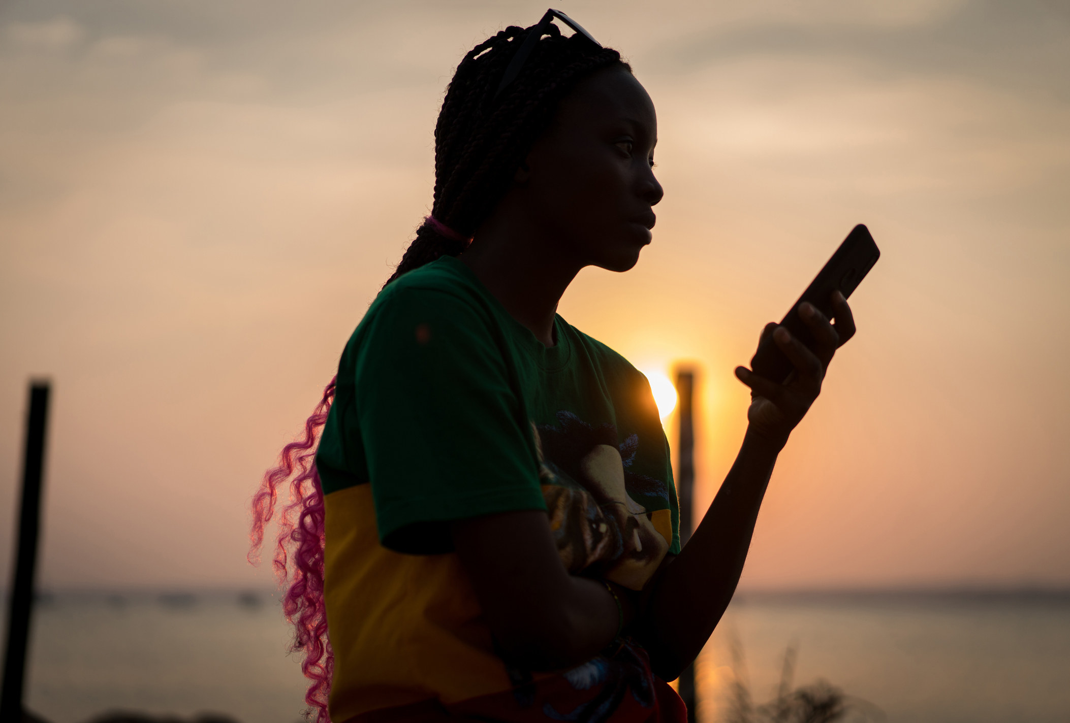 A teen holds their phone outside, alone