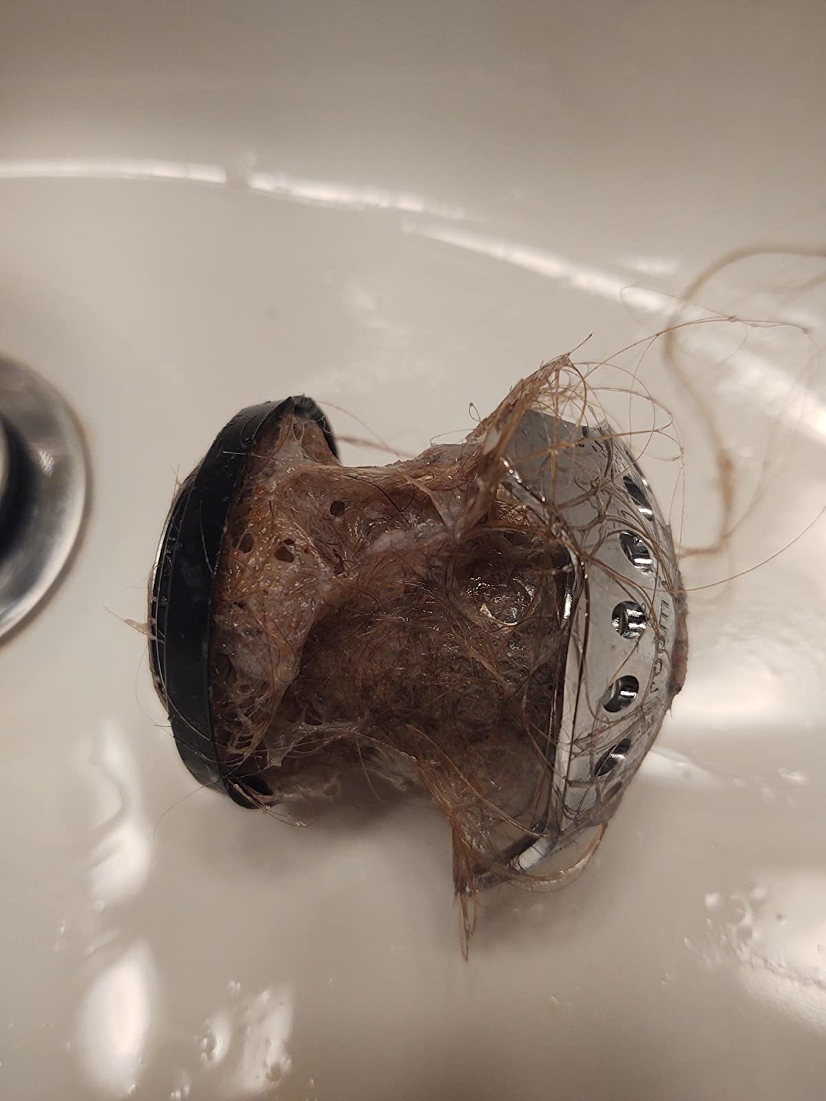 reviewer image of a stainless steel tubshroom covered in wet strands of hair