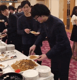 An Asian man serves himself noodles but then swaps out the main plate for his smaller plate.