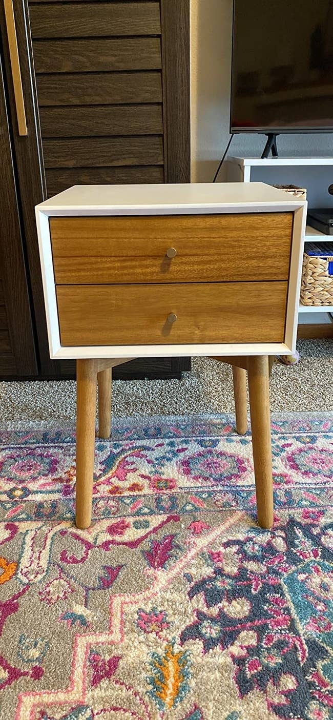 The square nightstand with four round legs and three drawers with circular handles