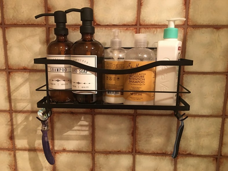 The shower caddy in black on a reviewer&#x27;s bathroom wall 